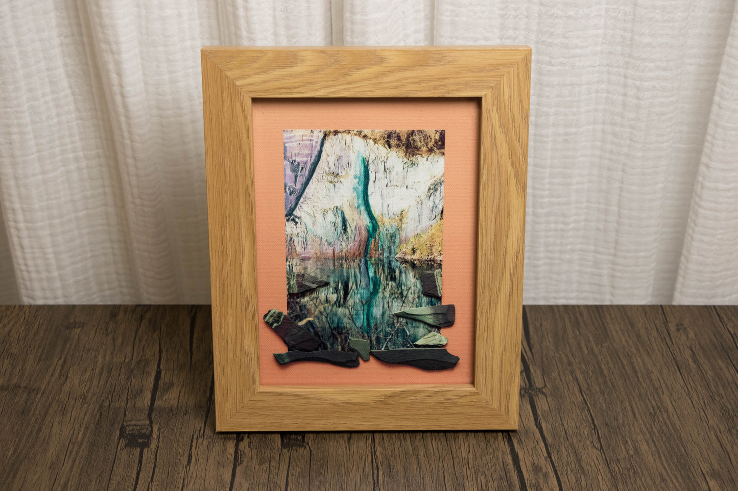 Framed abstract artwork on a wooden floor with a neutral background
