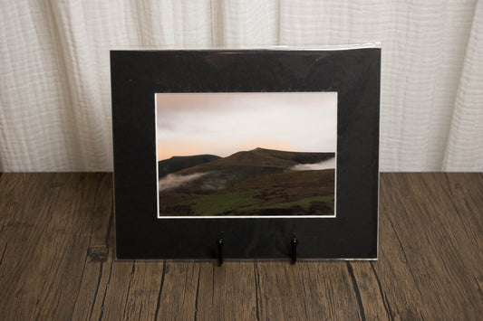 Framed landscape photo on a wooden surface with a white curtain background