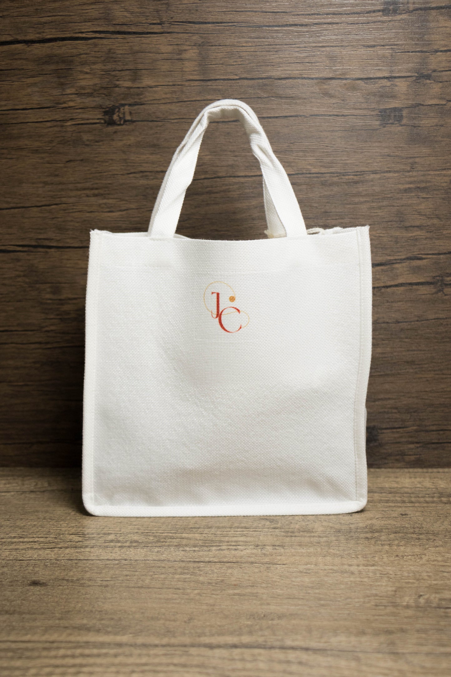 Back of a  white tote bag with a small logo 