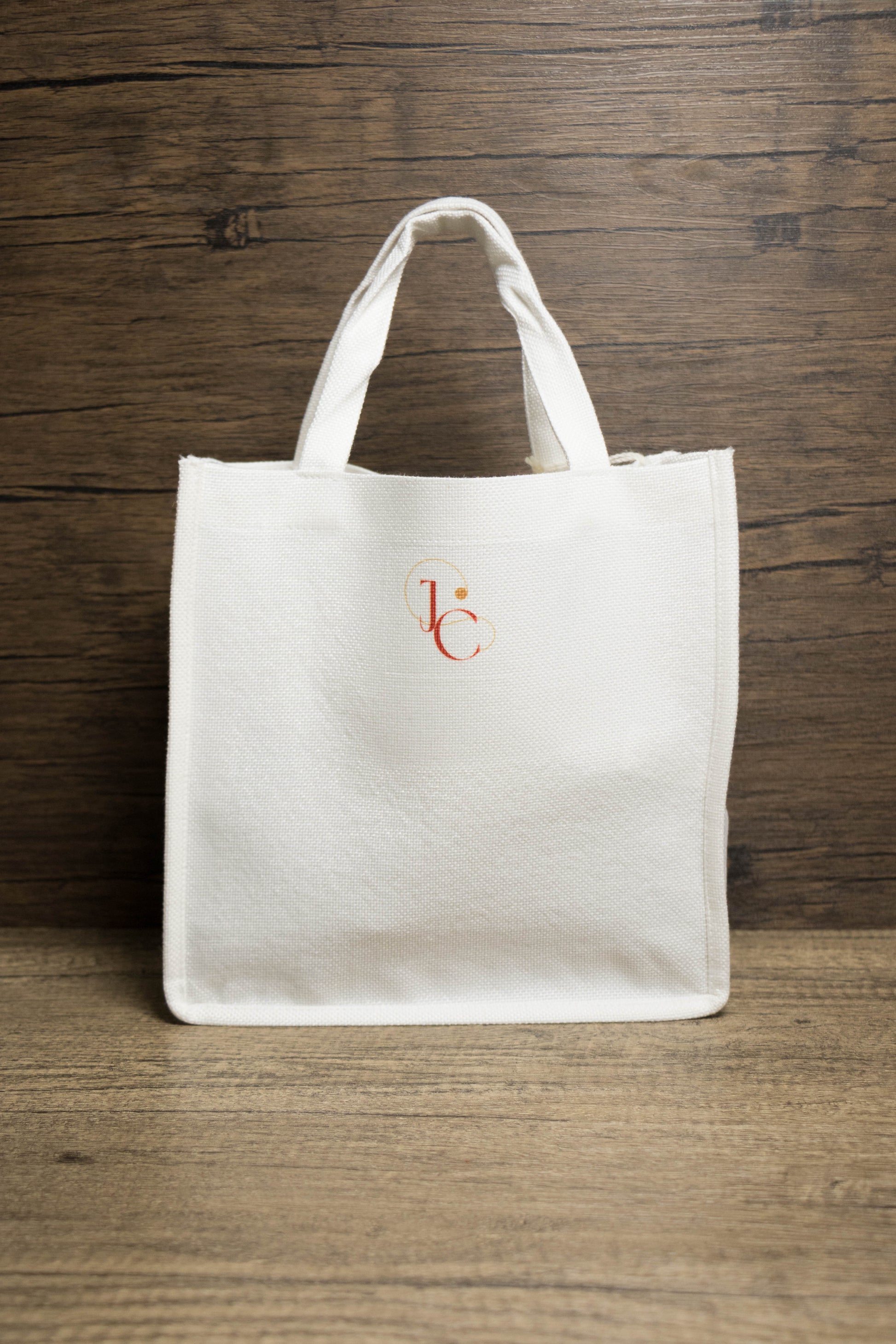Back of a  white tote bag with a small logo 