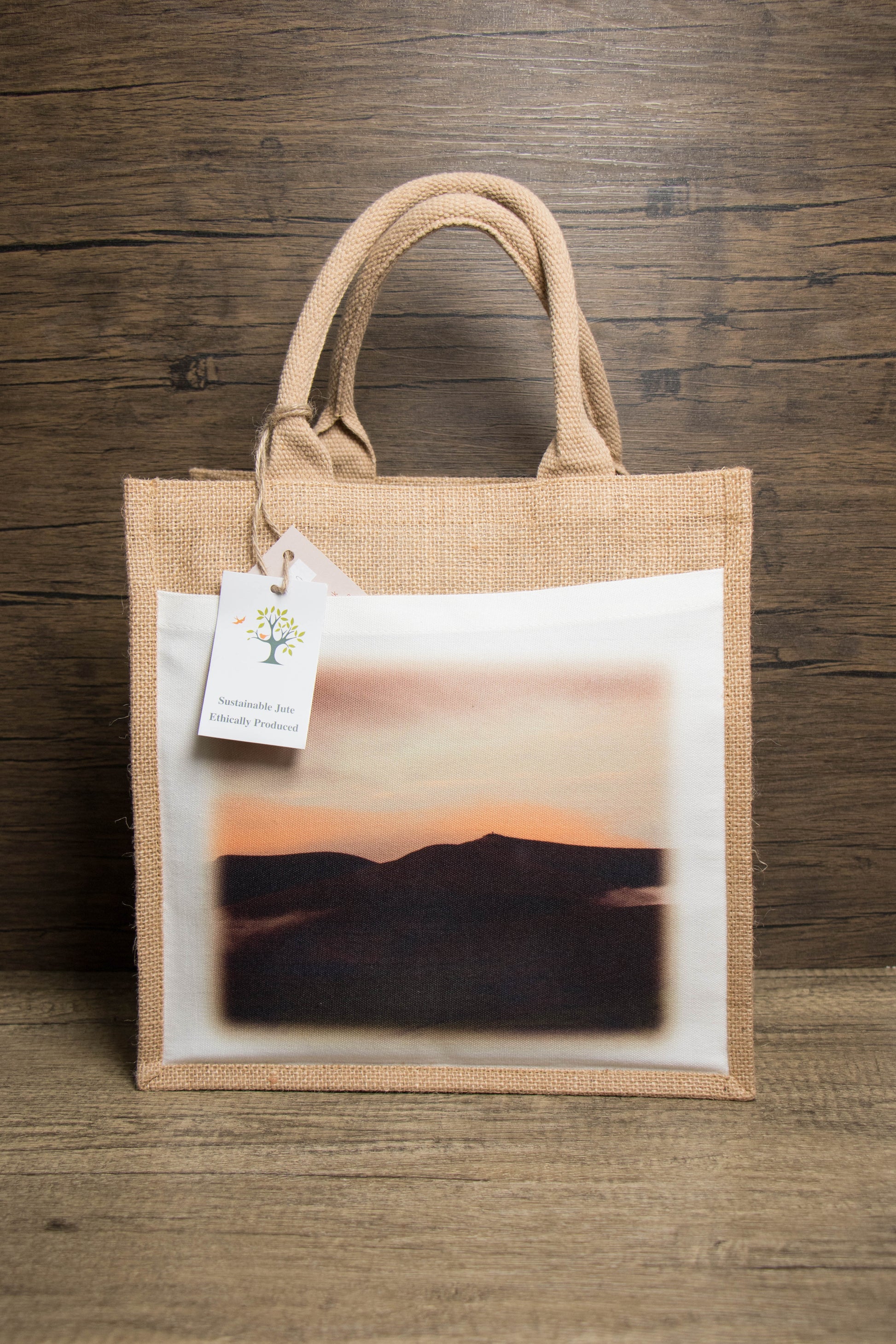 jute bag with sunset mountain landscape with a ticket that says sustainable jute ethically produce